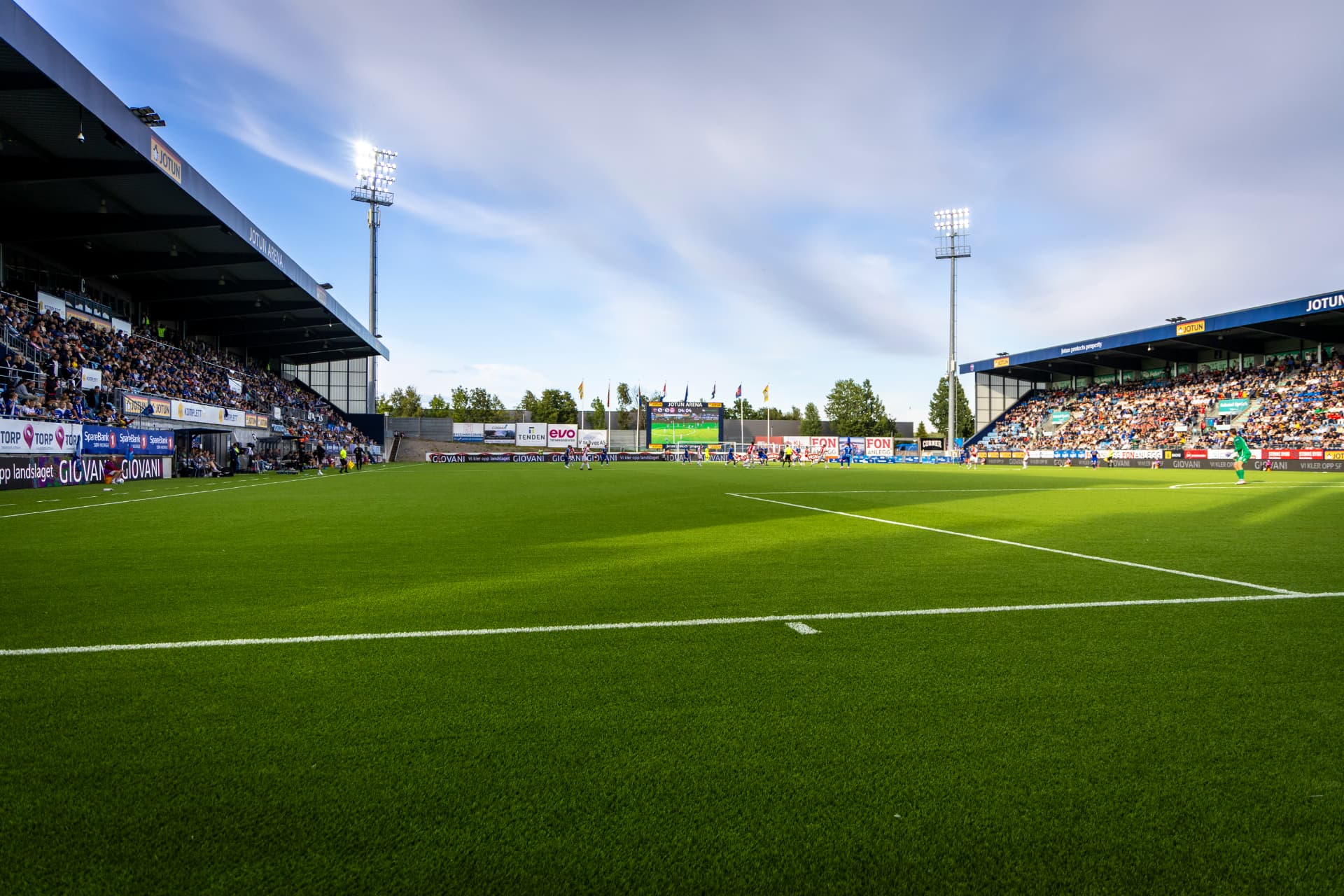 Jotun Arena sett fra banen om kvelden, med tribune og flomlys