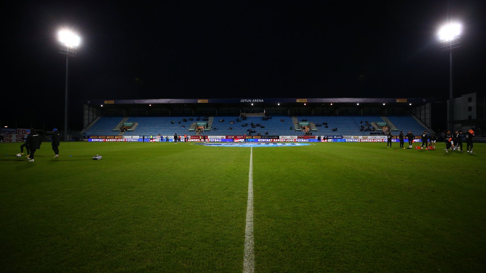 Jotun Arena sett fra banen om kvelden, med tribune og flomlys